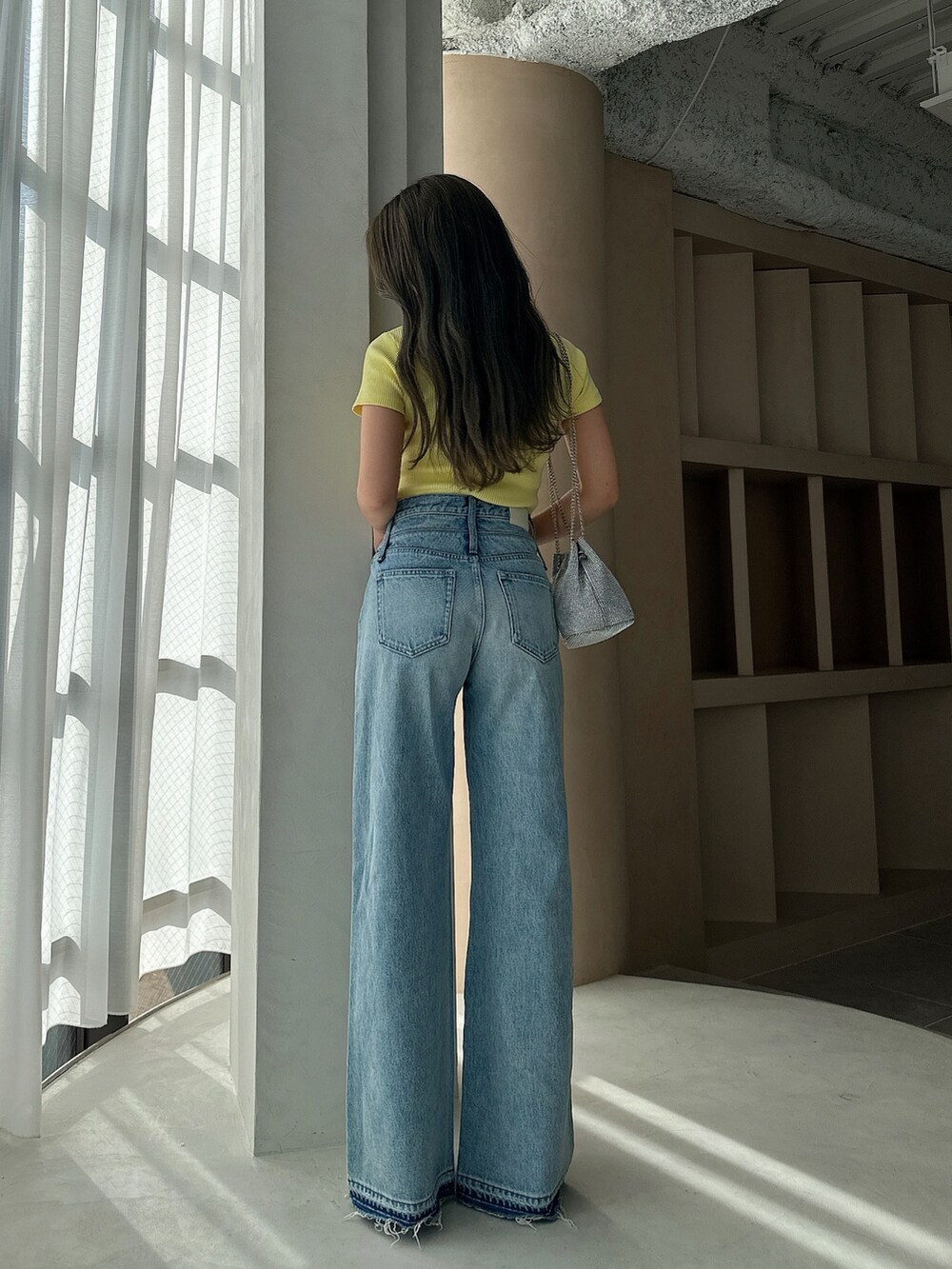 イエロー系のTシャツ/カットソー、シルバー系のショルダーバッグ、ブルー系のデニムパンツを着用したレディースの夏コーディネートの3枚目の写真