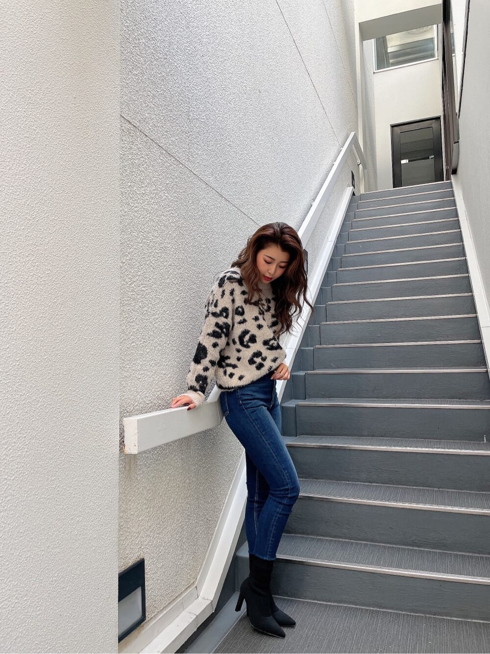 ホワイト系のニット/セーター、ブルー系のデニムパンツ、ブラック系のブーツを着用したレディースの秋コーディネートの3枚目の写真