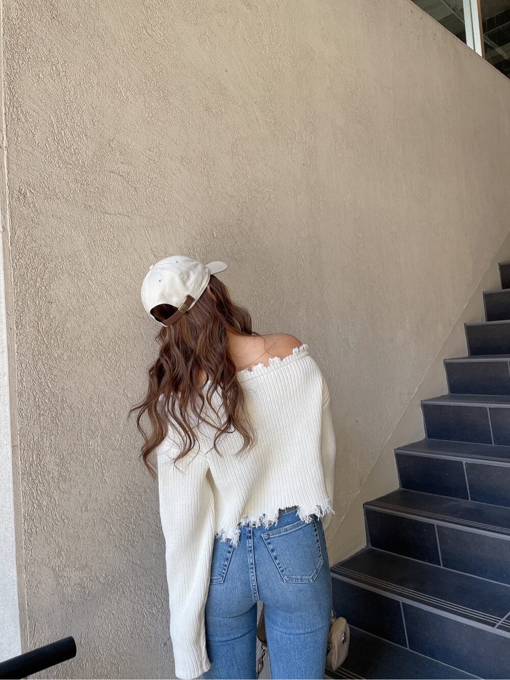 ホワイト系のニット/セーター、ホワイト系のパンプス、ブルー系のデニムパンツを着用したレディースの冬コーディネートの6枚目の写真