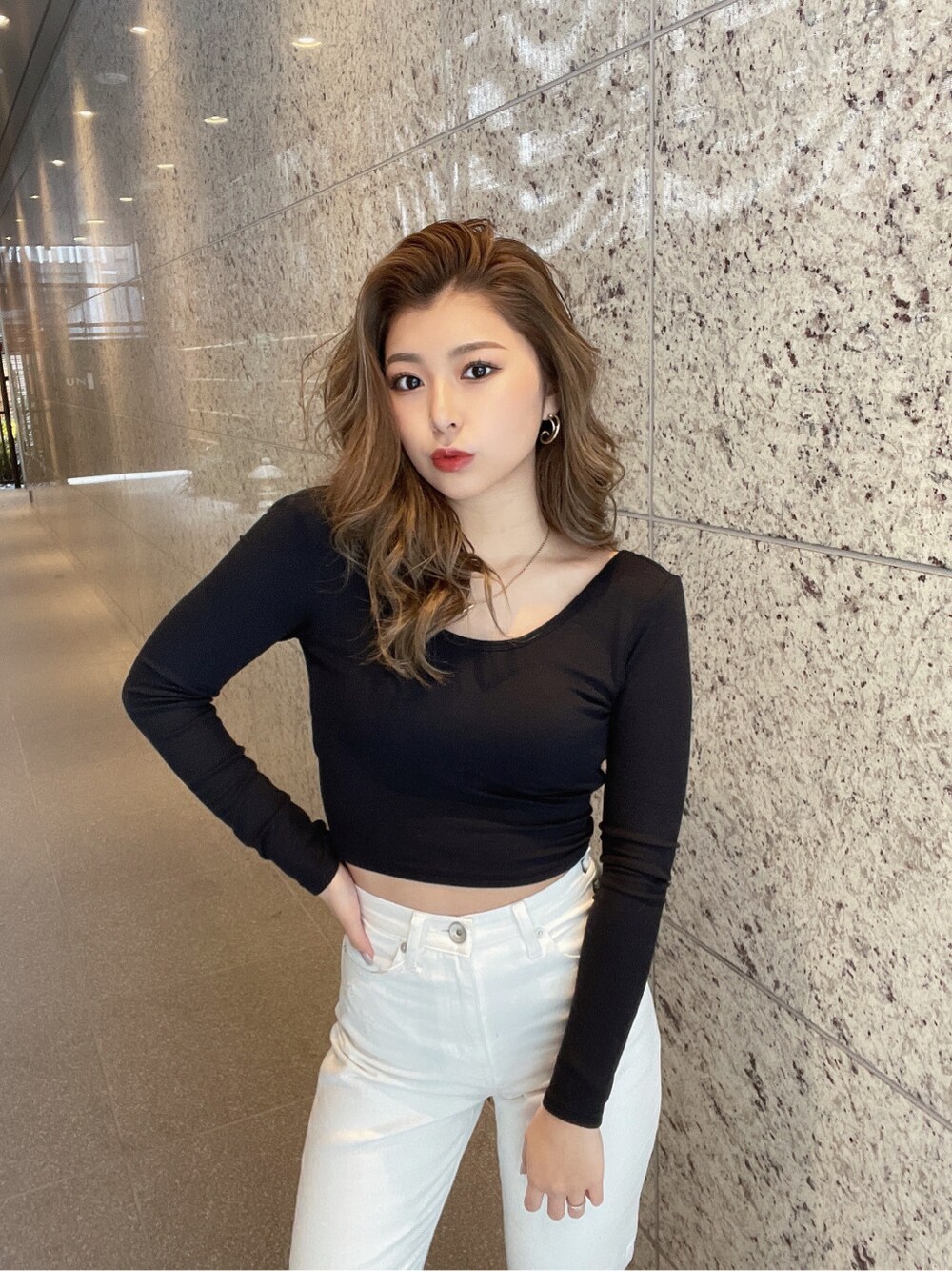 ホワイト系のパンプス、ホワイト系のデニムパンツ、ゴールド系のピアス(両耳用)を着用したレディースの冬コーディネートの6枚目の写真