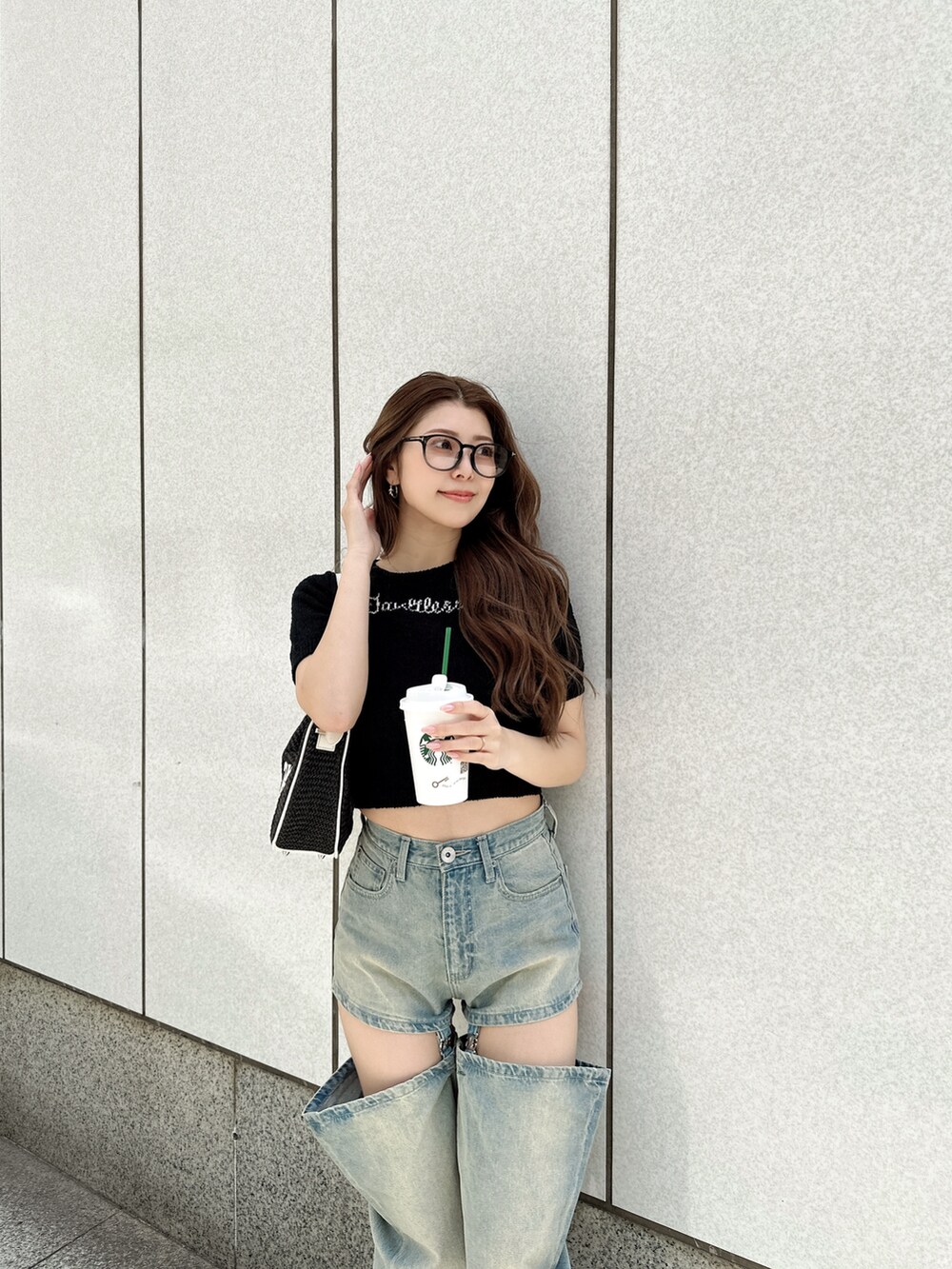 ブラック系のTシャツ/カットソー、ブラック系のハンドバッグ、ブルー系のデニムパンツを着用したレディースの夏コーディネートの2枚目の写真