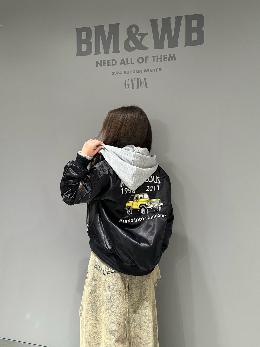 グレー系のパーカー、ブルー系のデニムスカート、ブラック系のブルゾンを着用したレディースの秋コーディネートの5枚目の写真