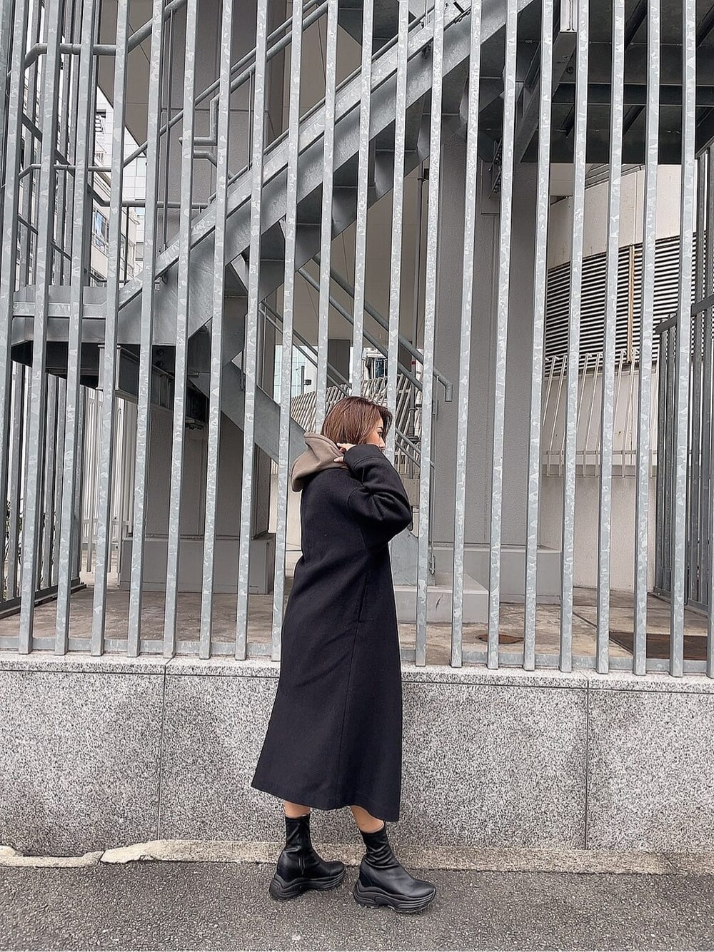 ブラック系のブーツ、ベージュ系のパーカー、ブラック系のチェスターコートを着用したレディースの秋コーディネートの2枚目の写真