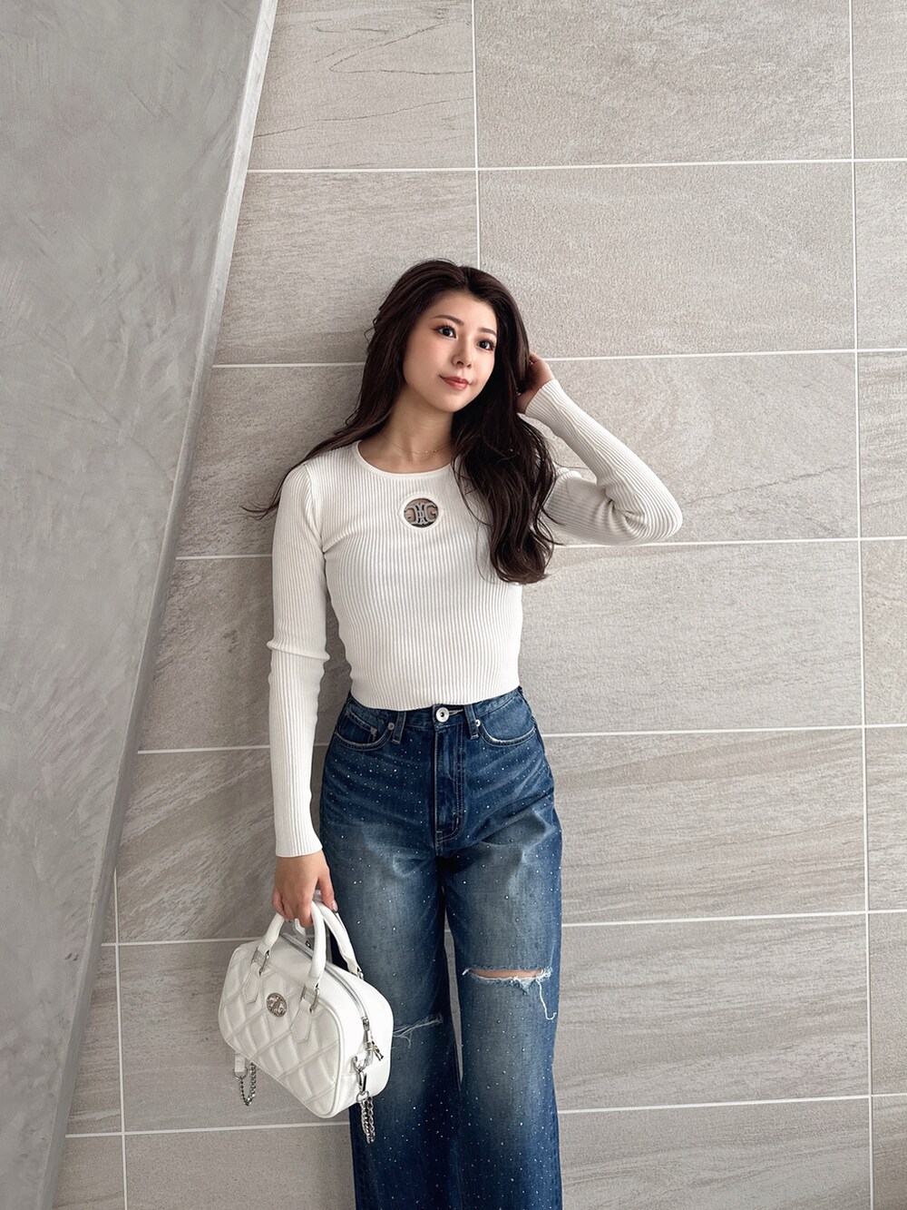 ブルー系のデニムパンツ、ホワイト系のパンプス、ホワイト系のハンドバッグを着用したレディースの冬コーディネートの3枚目の写真