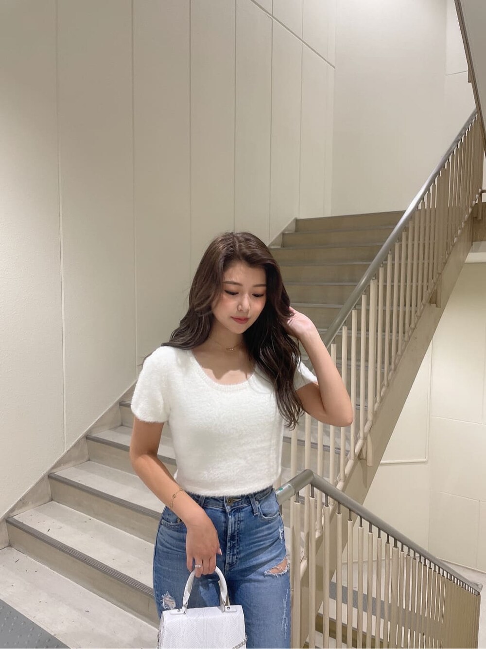 ホワイト系のニット/セーター、ホワイト系のハンドバッグ、ホワイト系のパンプスを着用したレディースの夏コーディネートの5枚目の写真