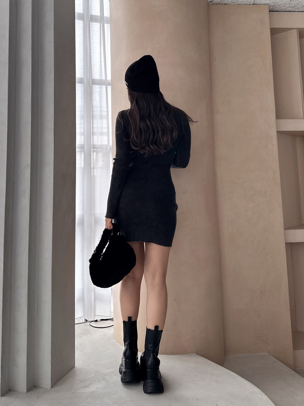 ブラック系のワンピース、ブラック系のブーツ、ブラック系のニットキャップ/ビーニーを着用したレディースの冬コーディネートの2枚目の写真