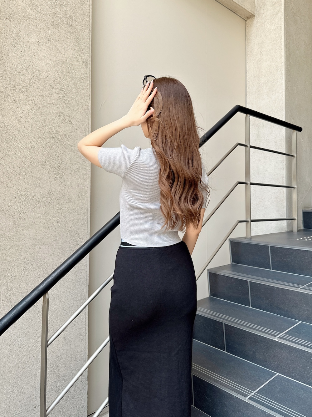 ホワイト系のパンプス、ブラック系のスカート、シルバー系のニット/セーターを着用したレディースの春コーディネートの6枚目の写真