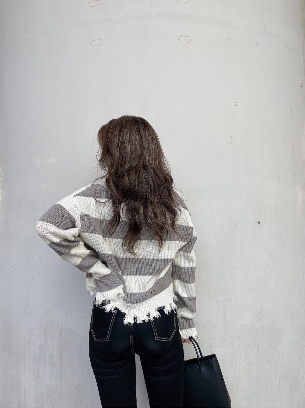 ブラック系のショルダーバッグ、ブラック系のデニムパンツ、グレー系のニット/セーターを着用したレディースの秋コーディネートの6枚目の写真