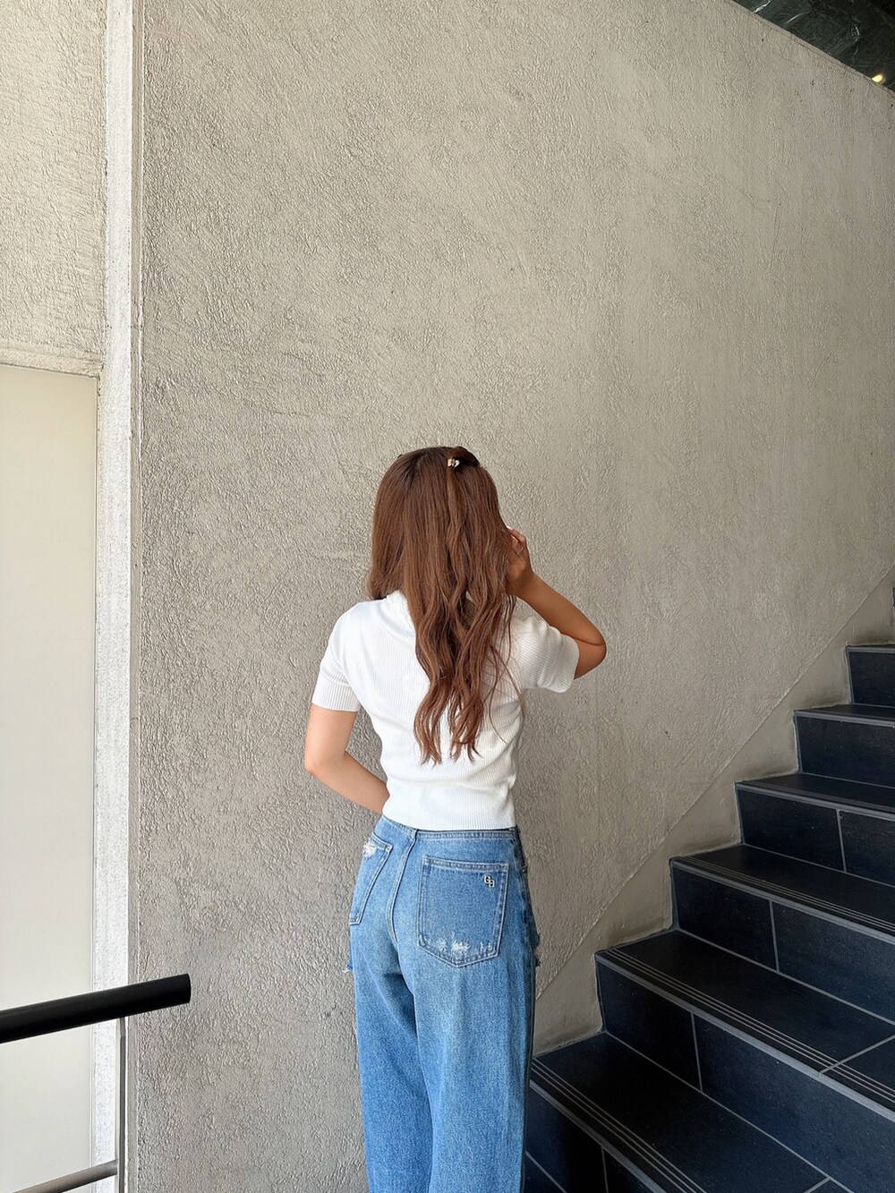 ホワイト系のニット/セーター、ブルー系のデニムパンツ、ブラック系のパンプスを着用したレディースの夏コーディネートの6枚目の写真