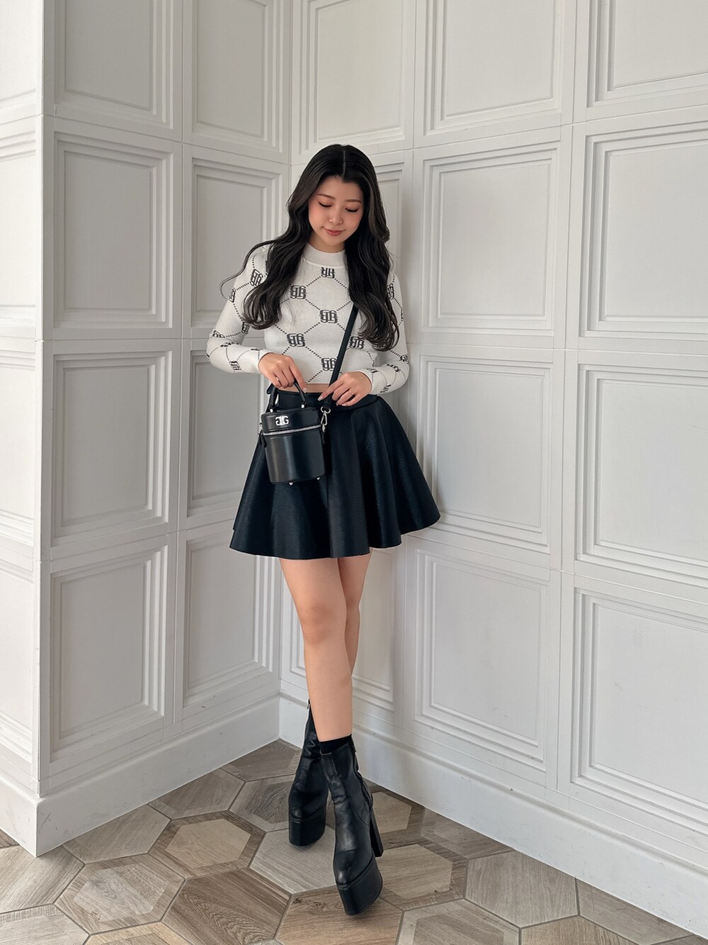 ブラック系のスカート、ブラック系のハンドバッグ、ホワイト系のニット/セーターを着用したレディースの冬コーディネートの3枚目の写真