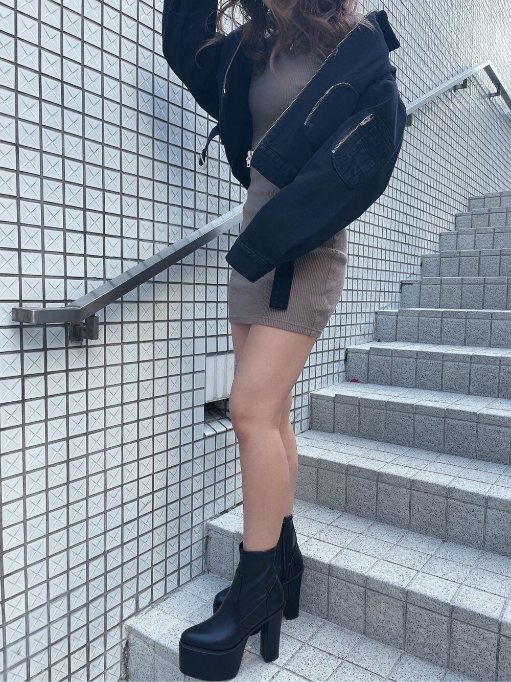 ブラック系のデニムジャケット、ベージュ系のワンピースを着用したレディースの冬コーディネートの2枚目の写真