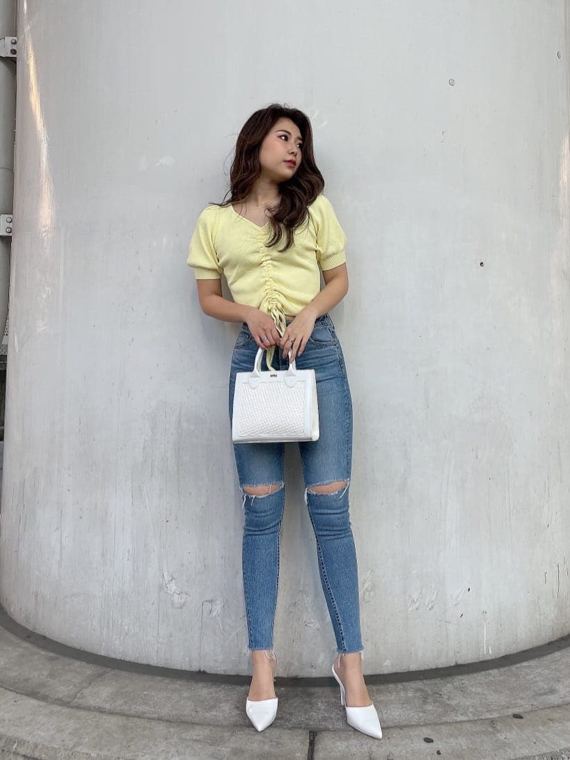 ホワイト系のパンプス、ホワイト系のハンドバッグ、ブルー系のデニムパンツを着用したレディースの春コーディネートの3枚目の写真