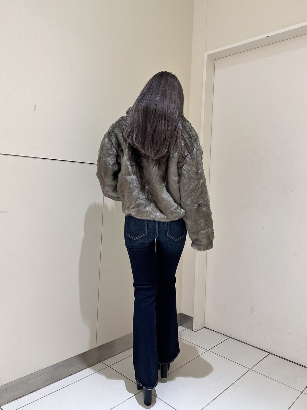 ブルー系のデニムパンツ、ホワイト系のニット/セーター、ブラック系のブーツを着用したレディースの秋コーディネートの2枚目の写真