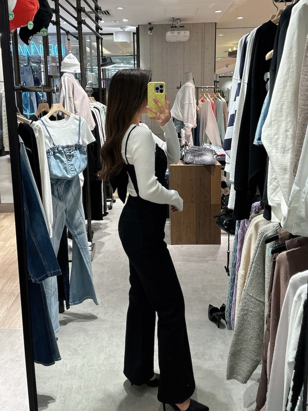 ブラック系のサロペット/オーバーオール、ホワイト系のニット/セーター、ブラック系のパンプスを着用したレディースの春コーディネートの2枚目の写真