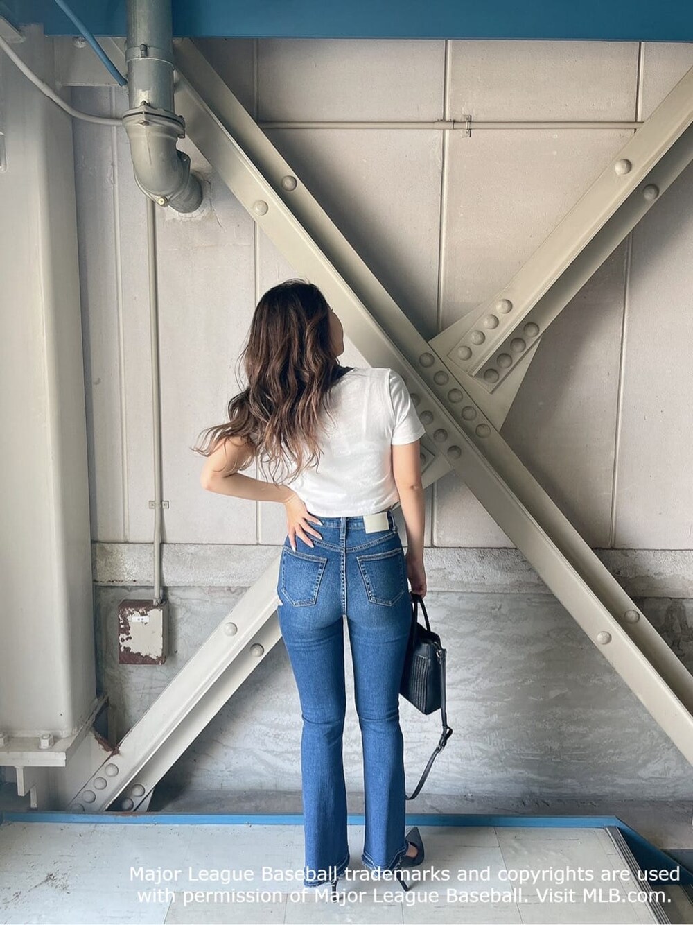 ブラック系のパンプス、ベージュ系のTシャツ/カットソー、ブルー系のデニムパンツを着用したレディースの夏コーディネートの2枚目の写真