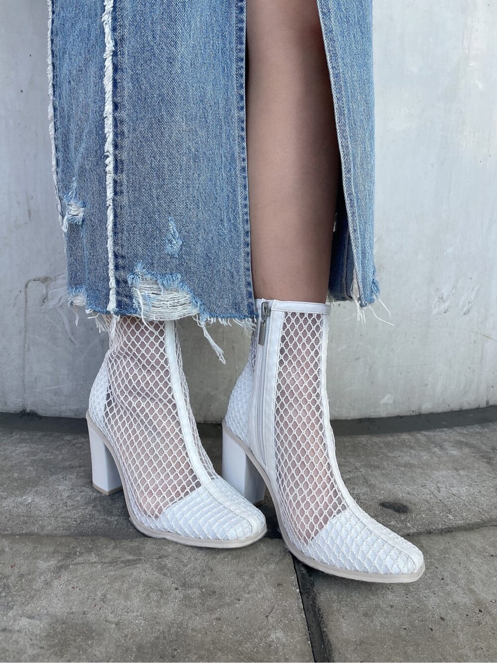 ホワイト系のブーツ、オレンジ系のスウェット、ブルー系のデニムスカートを着用したレディースの冬コーディネートの9枚目の写真