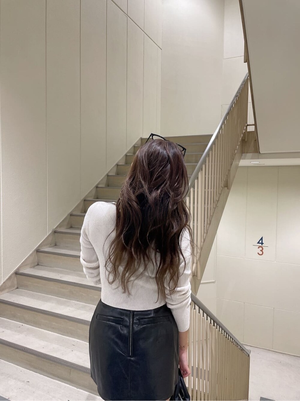 ブラック系のハンドバッグ、ブラック系のスカート、ホワイト系のカーディガン/ボレロを着用したレディースの秋コーディネートの5枚目の写真