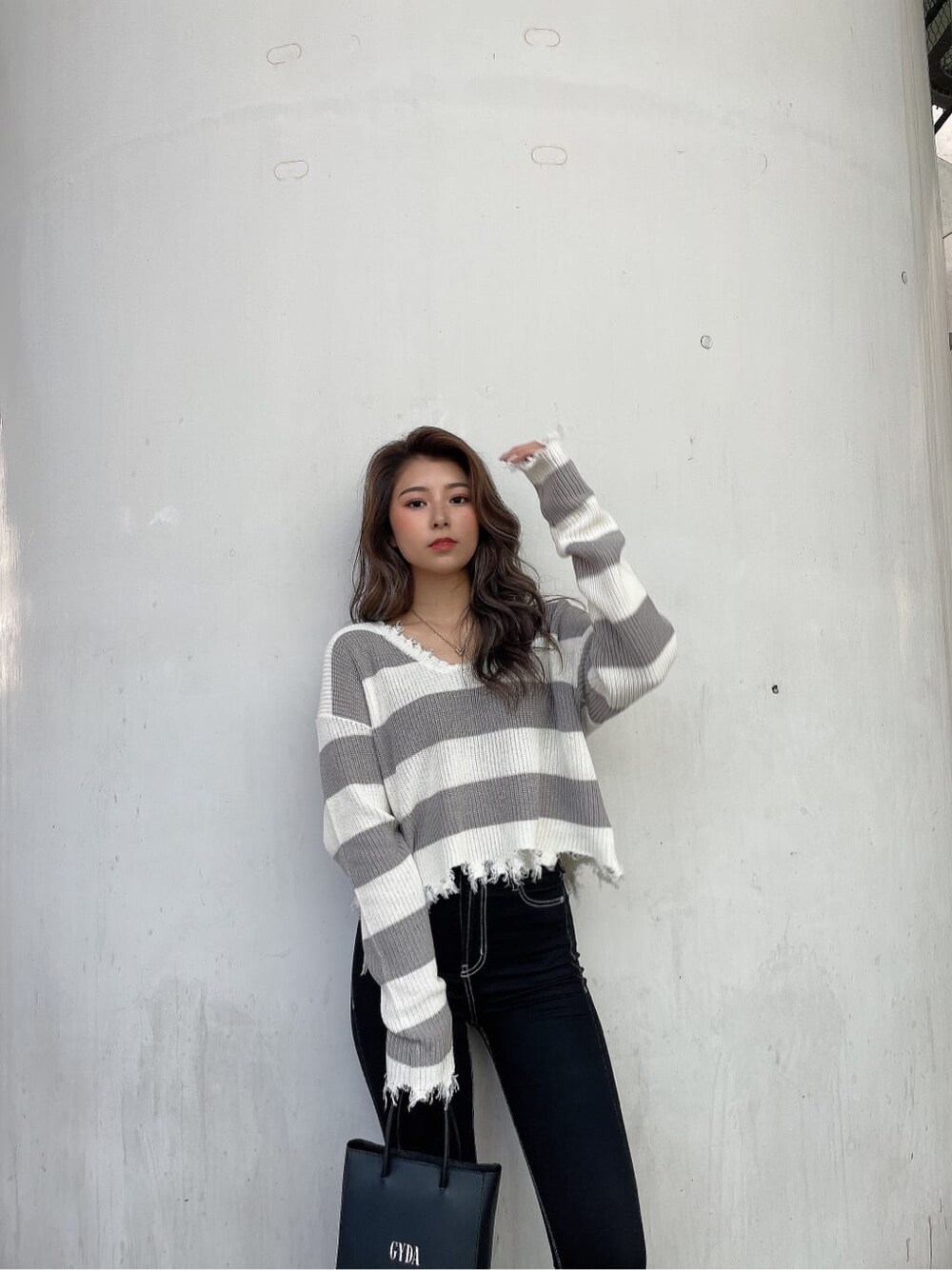 ブラック系のショルダーバッグ、ブラック系のデニムパンツ、グレー系のニット/セーターを着用したレディースの秋コーディネートの5枚目の写真