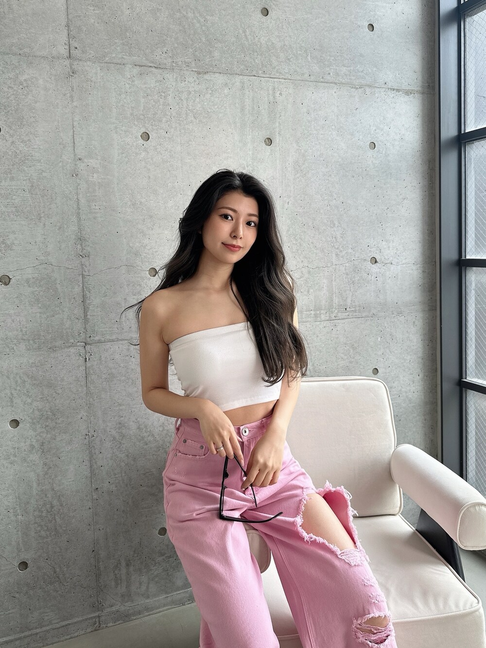 ピンク系のデニムパンツ、ホワイト系のパンプス、ホワイト系のチューブトップを着用したレディースの夏コーディネートの5枚目の写真