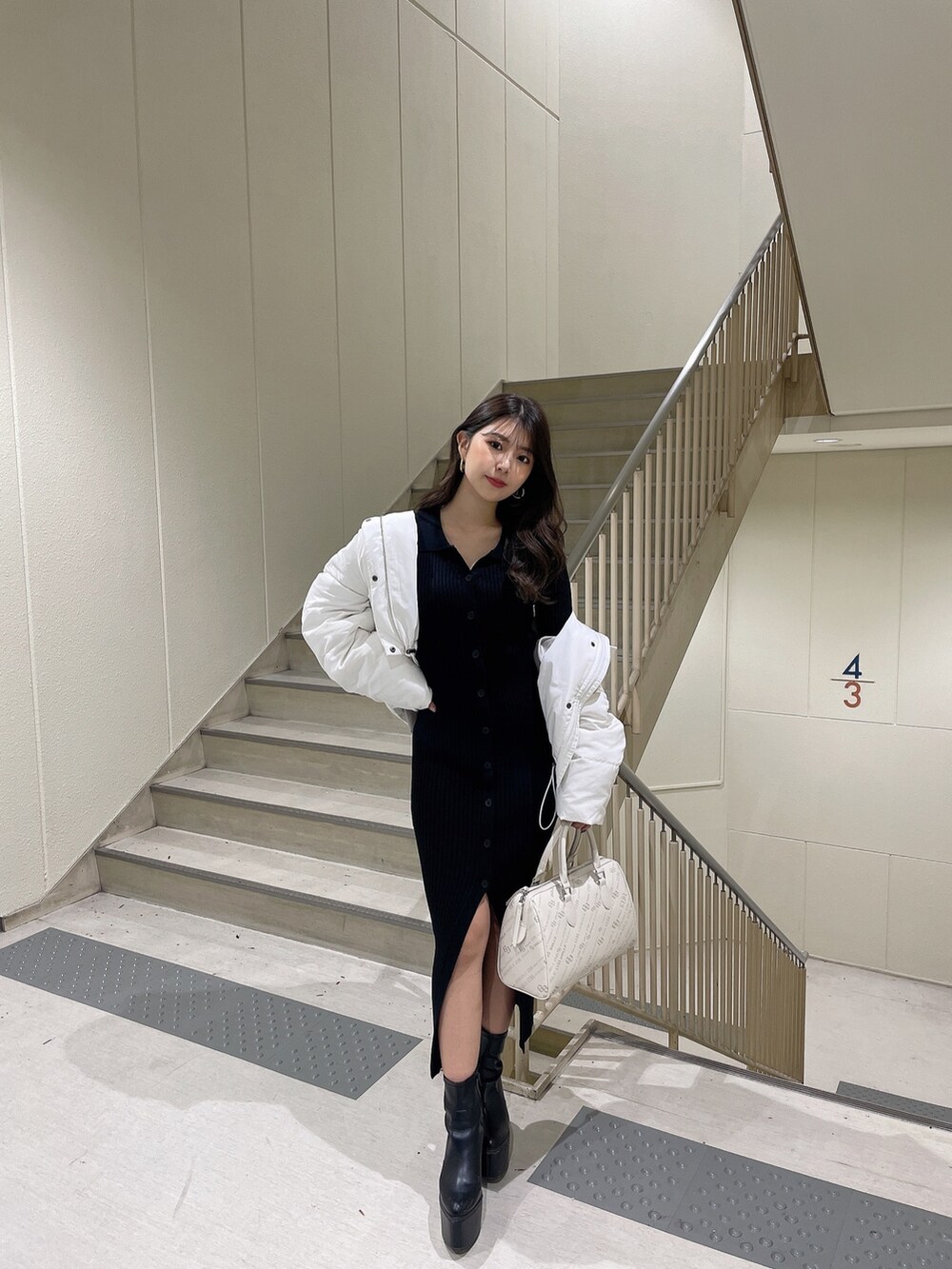 ブラック系のワンピース、ブラック系のダウンジャケット/コート、ブラック系のブーツを着用したレディースの冬コーディネートの3枚目の写真