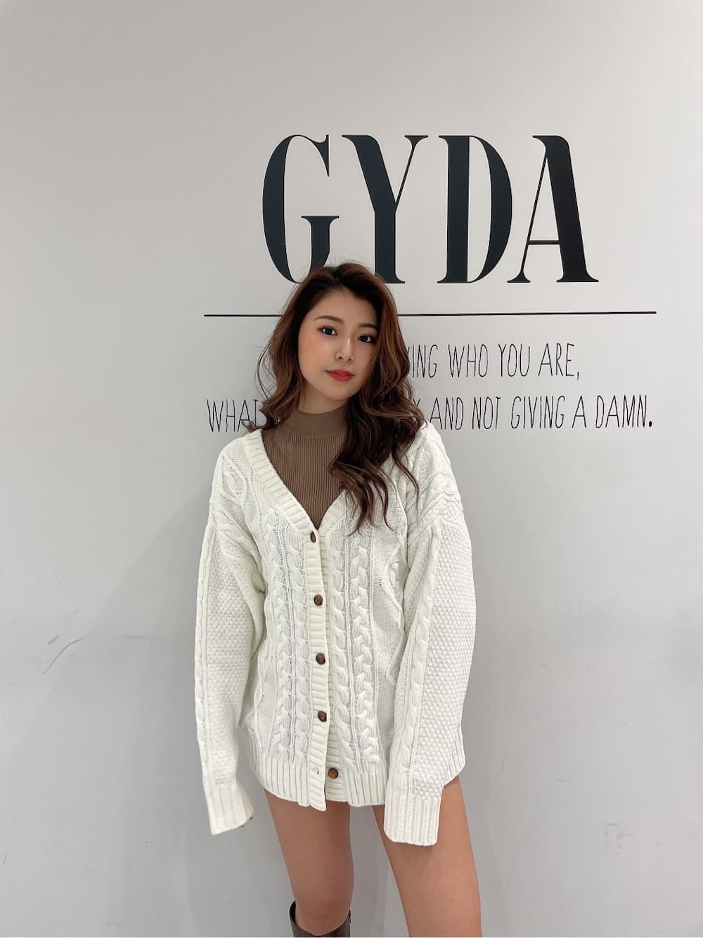 ブラック系のデニムパンツ、ブラウン系のブーツ、ベージュ系のニット/セーターを着用したレディースの秋コーディネートの4枚目の写真