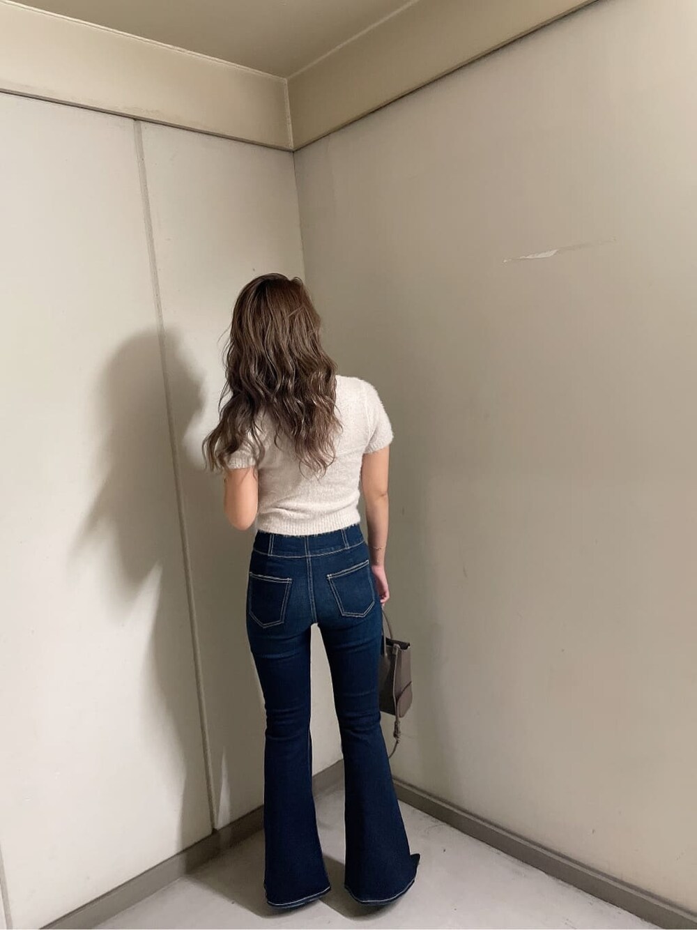 ブラック系のパンプス、ブルー系のデニムパンツ、ベージュ系のショルダーバッグを着用したレディースの夏コーディネートの5枚目の写真