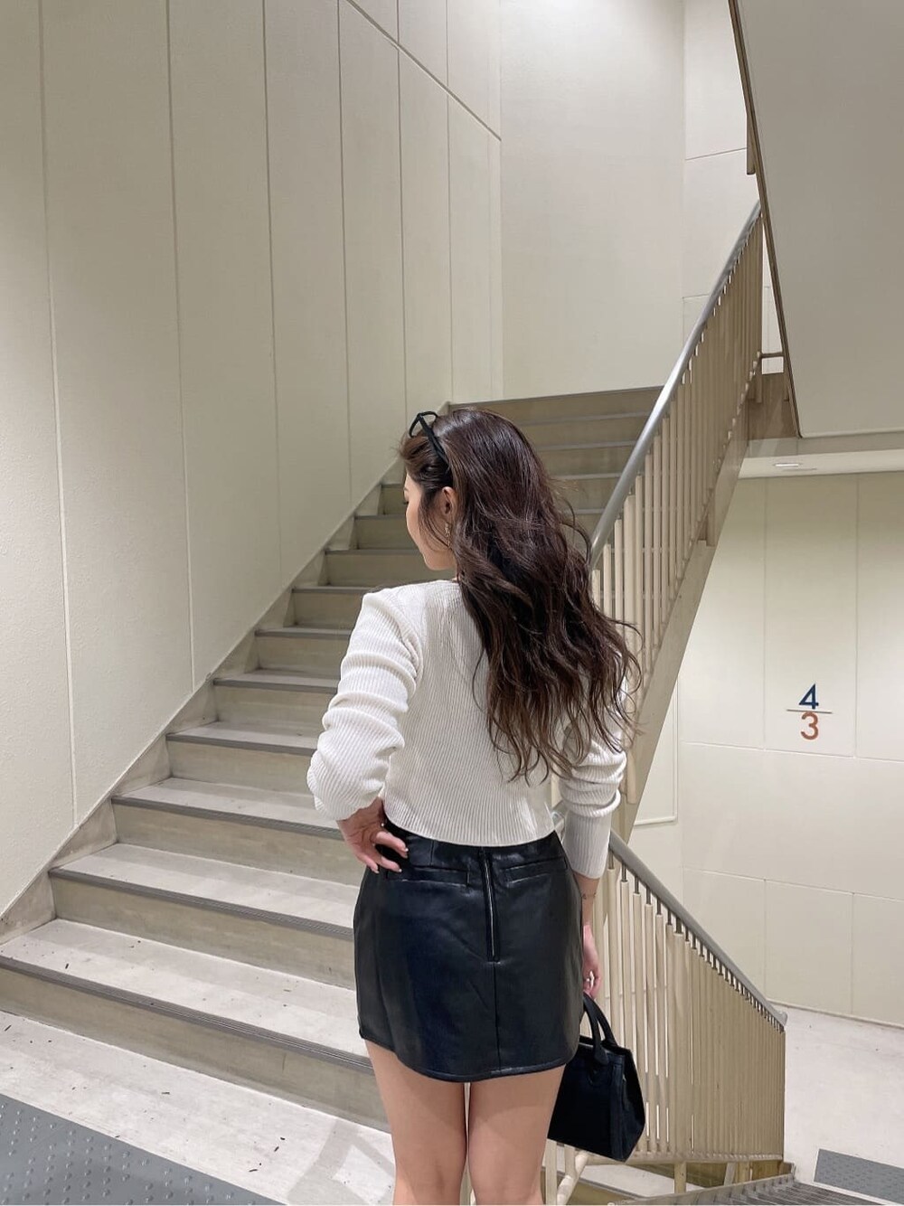 ブラック系のハンドバッグ、ブラック系のスカート、ホワイト系のカーディガン/ボレロを着用したレディースの秋コーディネートの7枚目の写真