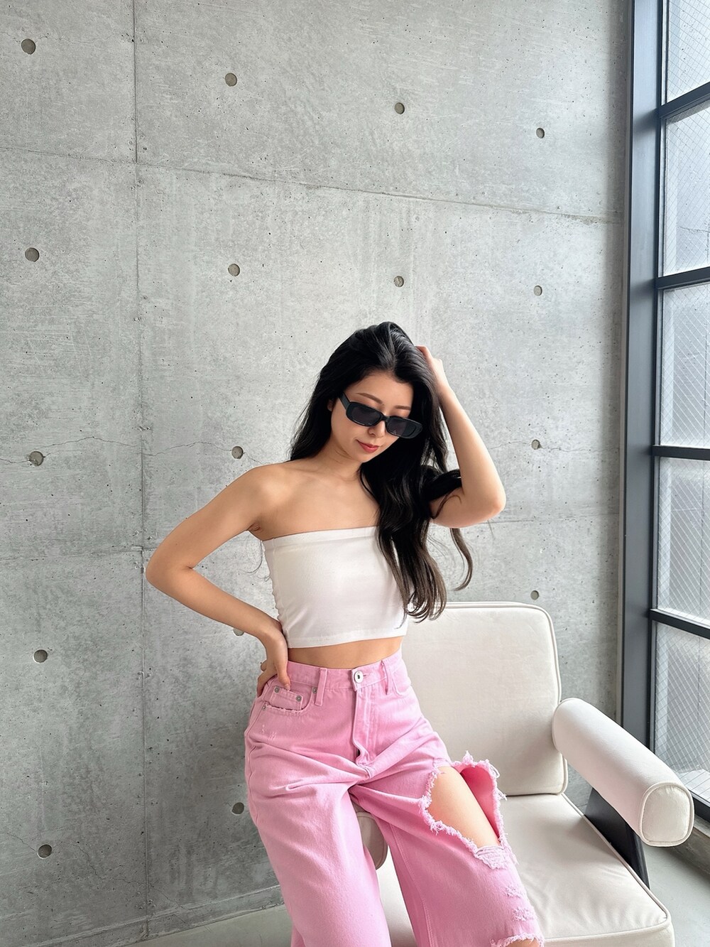 ピンク系のデニムパンツ、ホワイト系のパンプス、ホワイト系のチューブトップを着用したレディースの夏コーディネートの4枚目の写真