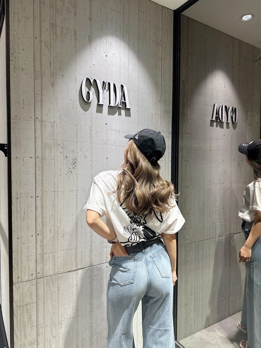 ブルー系のデニムパンツ、ホワイト系のサンダルを着用したレディースの夏コーディネートの6枚目の写真