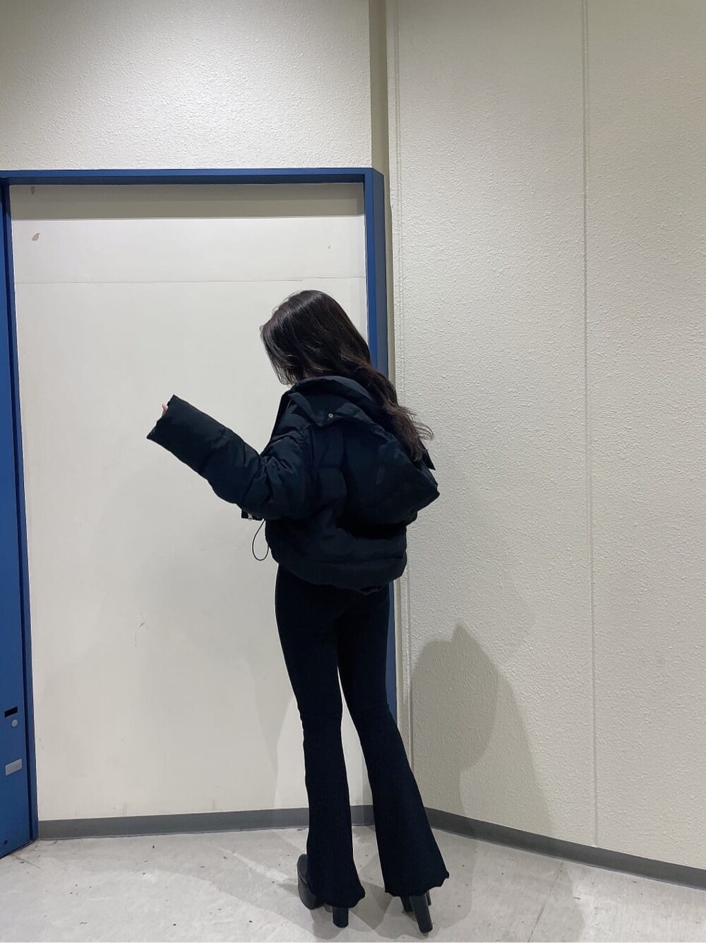 ブラック系のブーツ、ブラック系のダウンジャケット/コート、ホワイト系のニット/セーターを着用したレディースの秋コーディネートの4枚目の写真