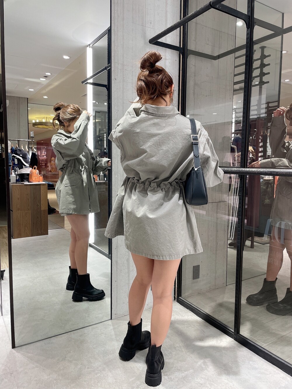 グレー系のミリタリージャケット、ホワイト系のハンドバッグ、ブラック系のブーツを着用したレディースの春コーディネートの4枚目の写真