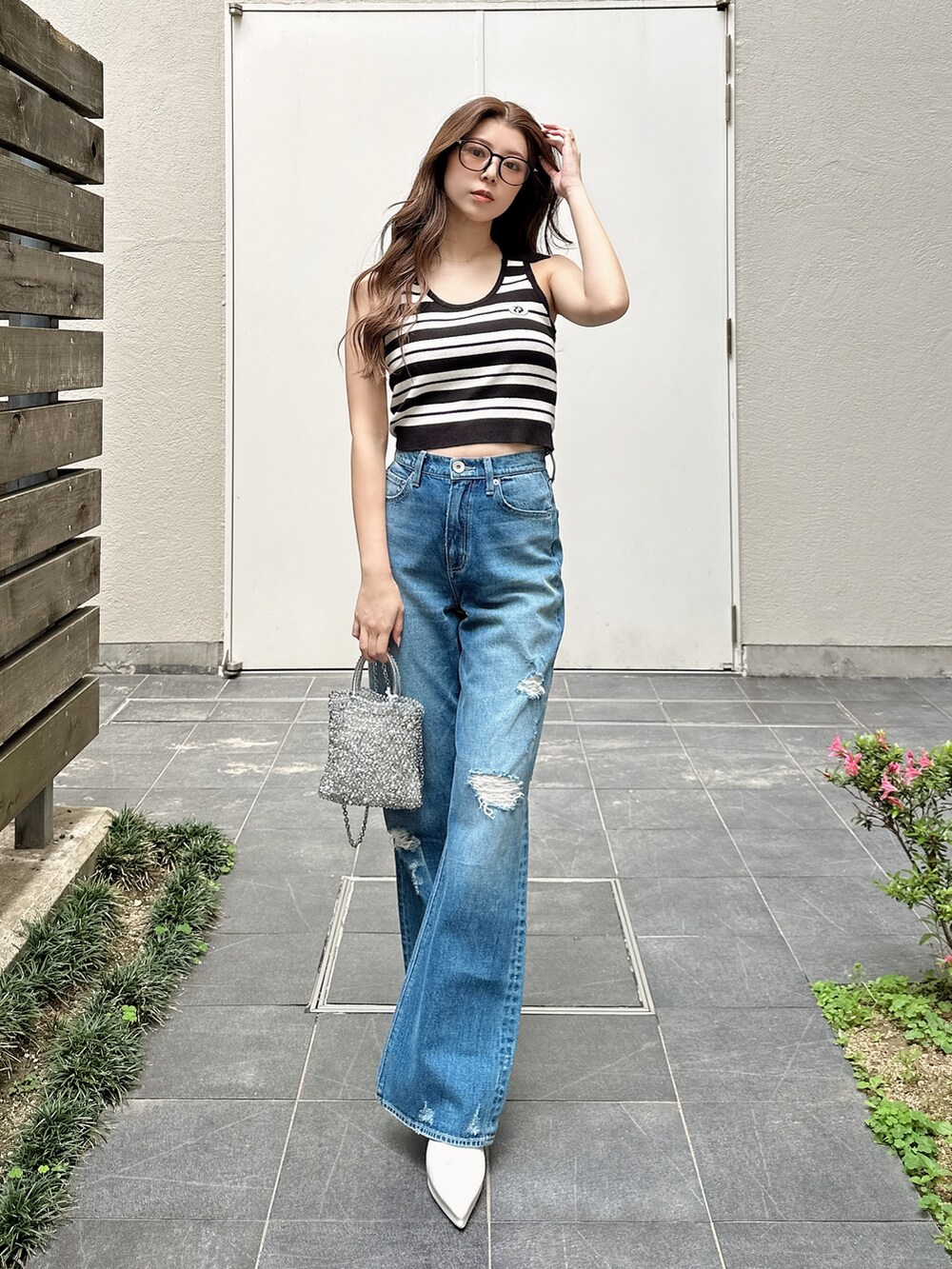 ブルー系のデニムパンツ、ホワイト系のパンプス、ホワイト系のニット/セーターを着用したレディースの夏コーディネートの2枚目の写真