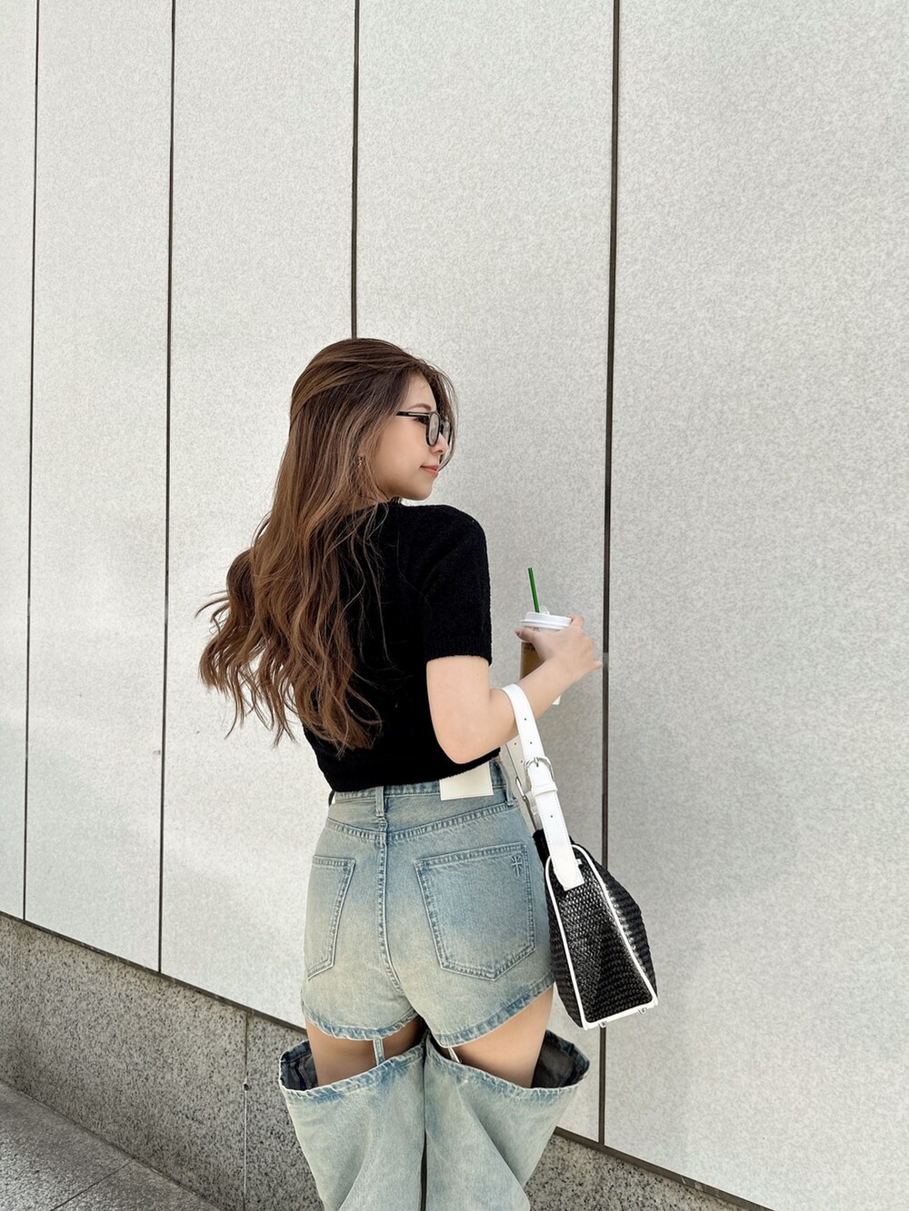 ブラック系のTシャツ/カットソー、ブラック系のハンドバッグ、ブルー系のデニムパンツを着用したレディースの夏コーディネートの3枚目の写真