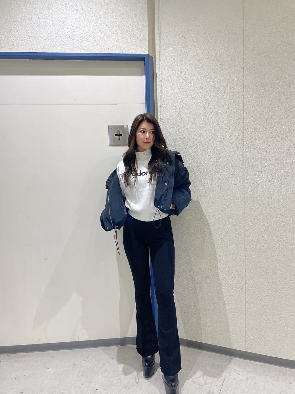 ブラック系のブーツ、ブラック系のダウンジャケット/コート、ホワイト系のニット/セーターを着用したレディースの秋コーディネートの2枚目の写真