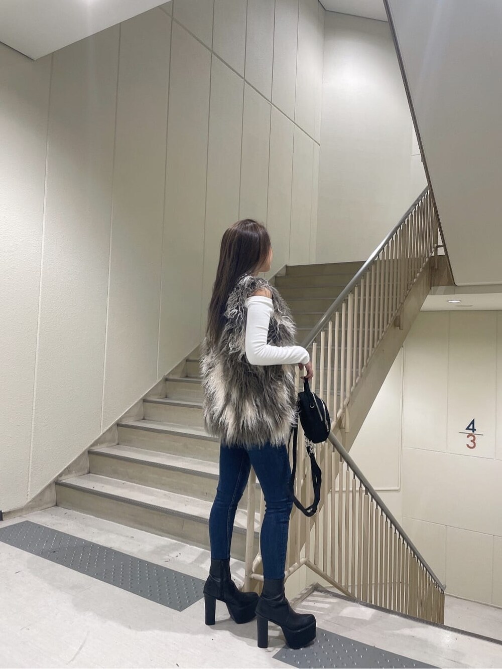 ブラック系のブーツ、ブルー系のデニムパンツ、ブラック系のバックパック/リュックを着用したレディースの秋コーディネートの4枚目の写真