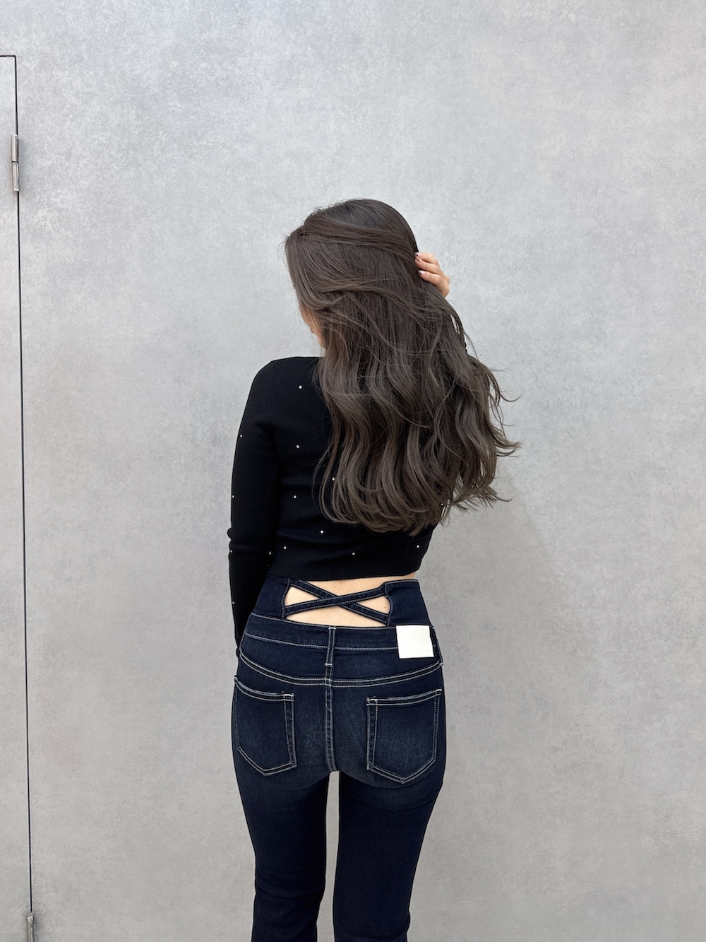 ブルー系のデニムパンツ、ブラック系のブーツ、ブラック系のニット/セーターを着用したレディースの冬コーディネートの4枚目の写真