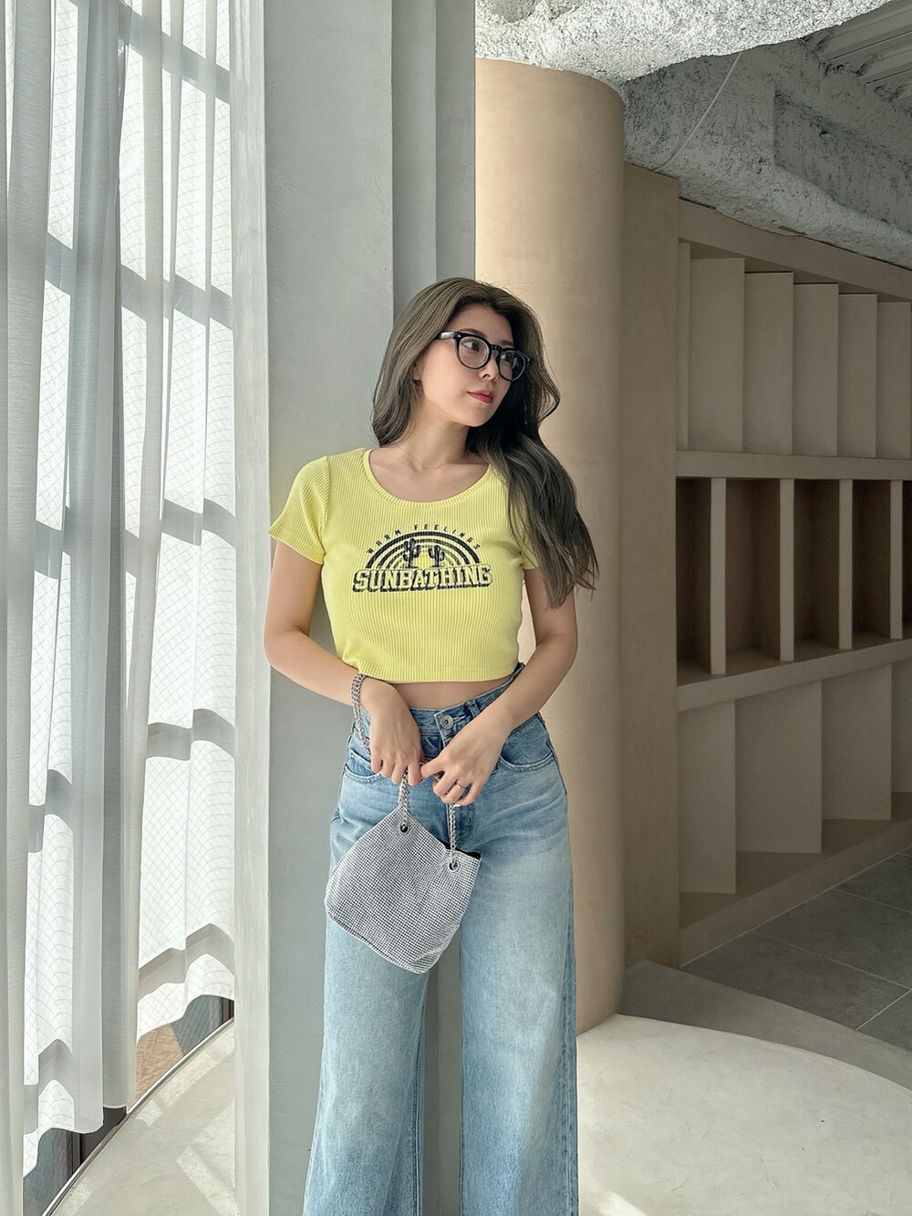 イエロー系のTシャツ/カットソー、シルバー系のショルダーバッグ、ブルー系のデニムパンツを着用したレディースの夏コーディネートの5枚目の写真