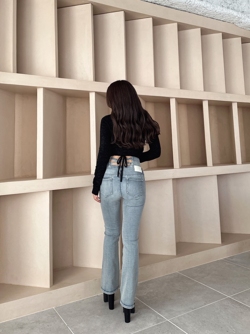 ブラック系のブーツ、ブルー系のデニムパンツ、ブラック系のニット/セーターを着用したレディースの秋コーディネートの2枚目の写真