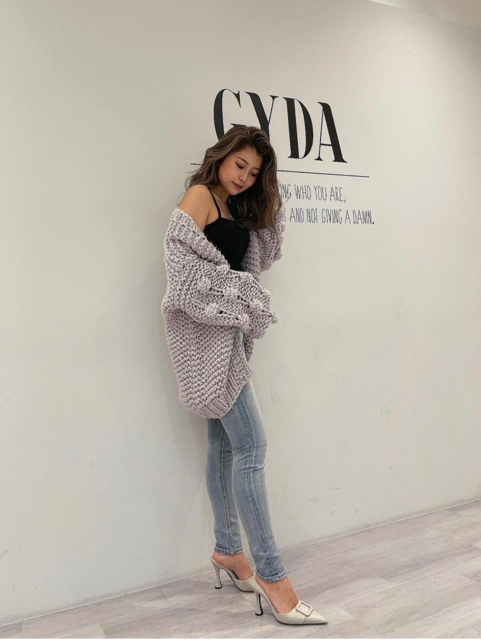 ホワイト系のパンプス、ブルー系のデニムパンツ、ブラック系のキャミソールを着用したレディースの冬コーディネートの2枚目の写真