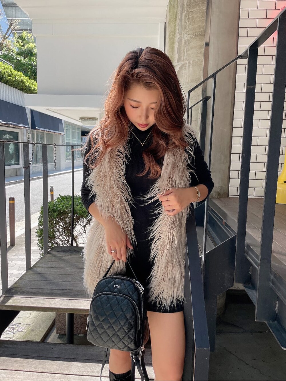 ブラック系のバックパック/リュック、ベージュ系のベスト、ブラック系のブーツを着用したレディースの秋コーディネートの6枚目の写真