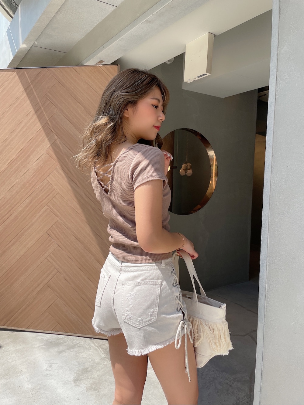 ベージュ系のサンダル、ホワイト系のハンドバッグ、ホワイト系のデニムパンツを着用したレディースの春コーディネートの4枚目の写真