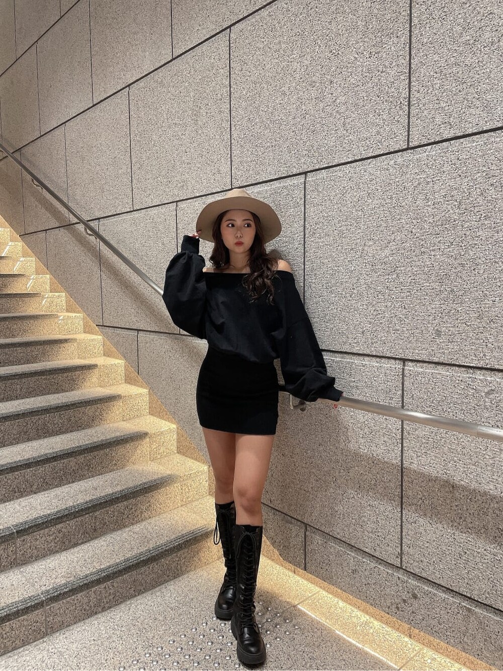 ブラック系のワンピース、ブラック系のブーツ、ベージュ系のハットを着用したレディースの秋コーディネートの2枚目の写真