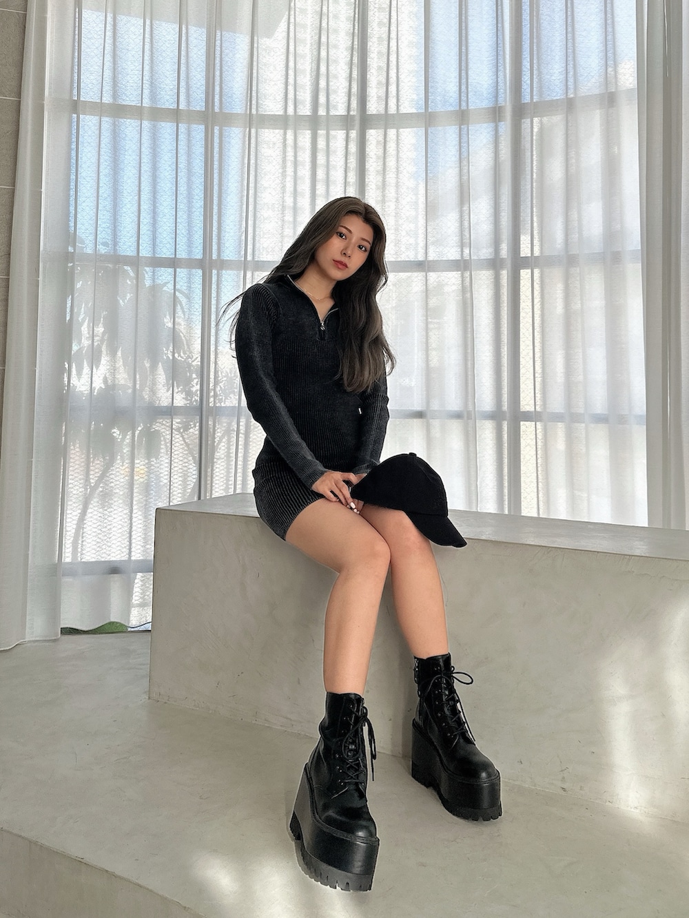 ブラック系のワンピース、ブラック系のブーツ、ブラック系のキャップを着用したレディースの秋コーディネートの2枚目の写真