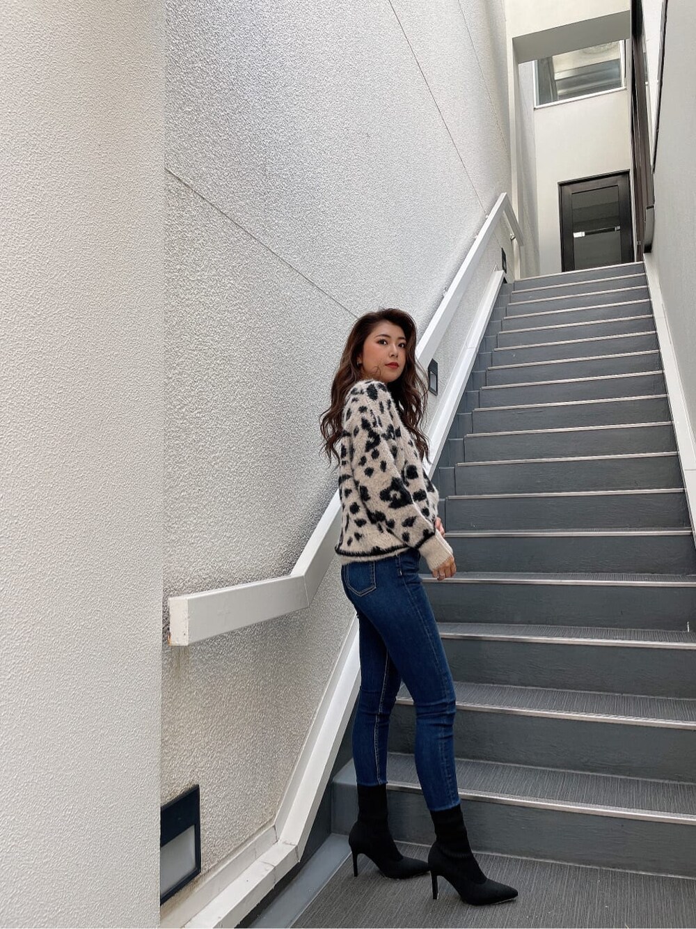 ホワイト系のニット/セーター、ブルー系のデニムパンツ、ブラック系のブーツを着用したレディースの秋コーディネートの5枚目の写真