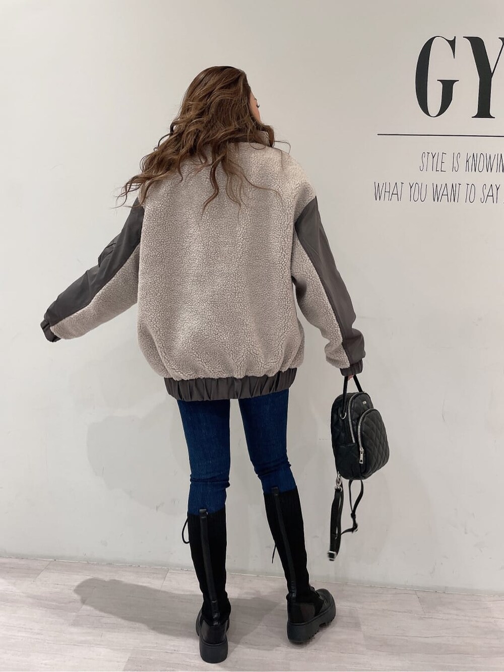 ブラック系のバックパック/リュック、ブラック系のブーツ、ブルー系のデニムパンツを着用したレディースの秋コーディネートの3枚目の写真