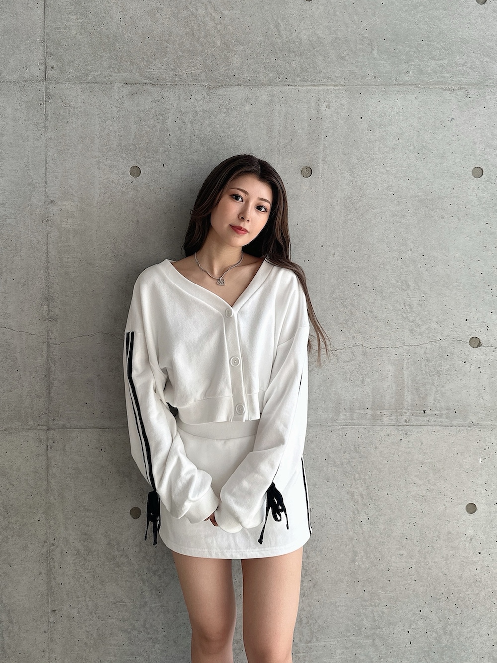 ホワイト系のカーディガン/ボレロ、ホワイト系のスカート、ブラック系のブーツを着用したレディースの秋コーディネートの2枚目の写真