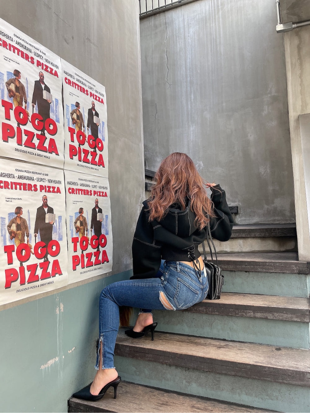 ブラック系のパンプス、ブルー系のデニムパンツ、ブラック系のパーカーを着用したレディースの秋コーディネートの3枚目の写真