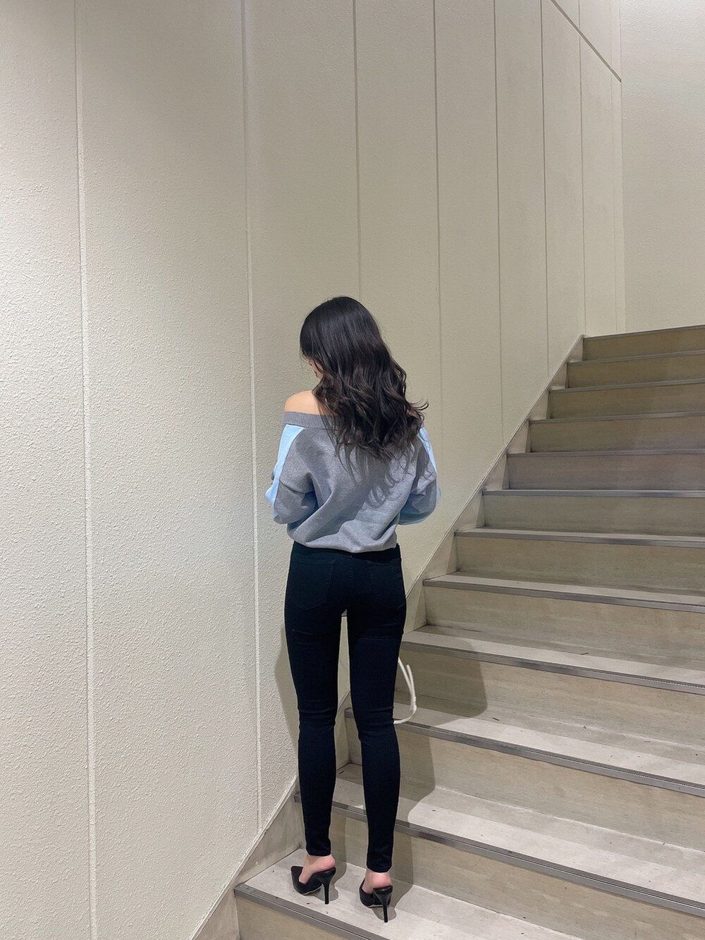 グレー系のニット/セーター、ブラック系のデニムパンツ、ホワイト系のパンプスを着用したレディースの冬コーディネートの3枚目の写真