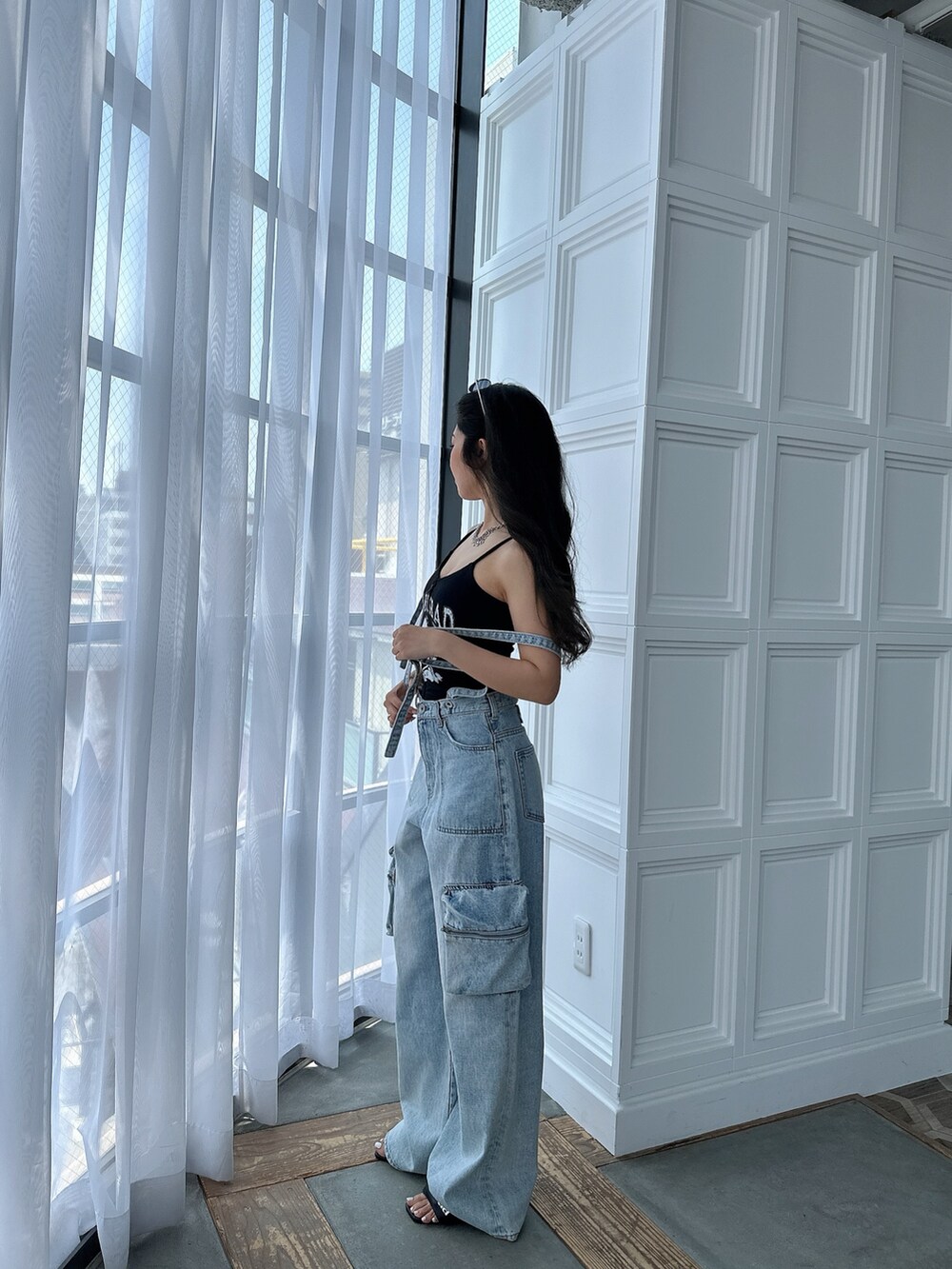 ブラック系のキャミソール、ブルー系のデニムパンツ、ブラック系のサンダルを着用したレディースの夏コーディネートの4枚目の写真