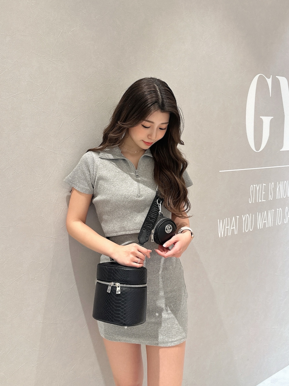 グレー系のワンピース、ブラック系のハンドバッグ、ブラック系のブーツを着用したレディースの春コーディネートの5枚目の写真